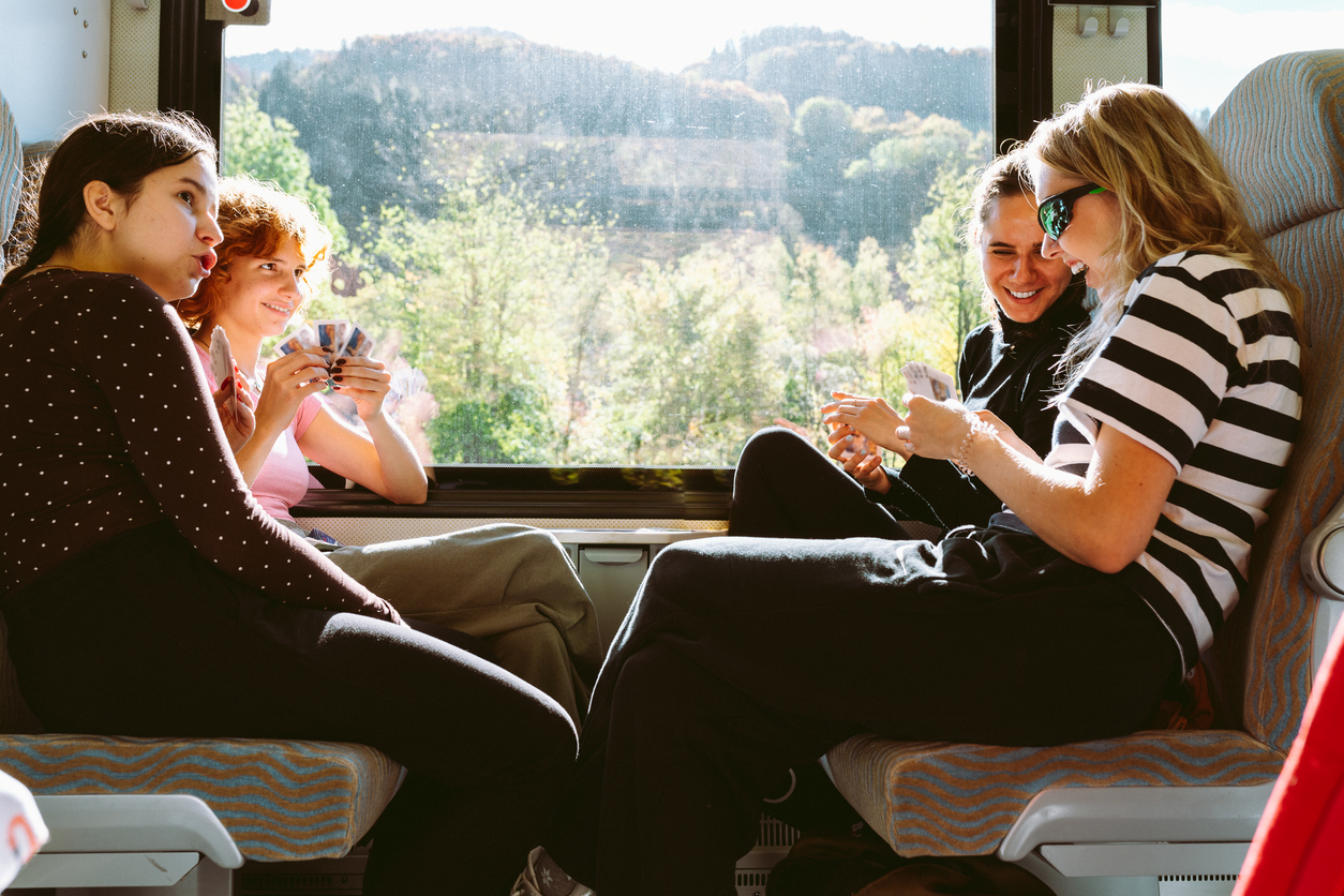 eine Gruppe von 4 Frauen sitzt auf einem 4er-Platz in der Bahn und spielt Karten