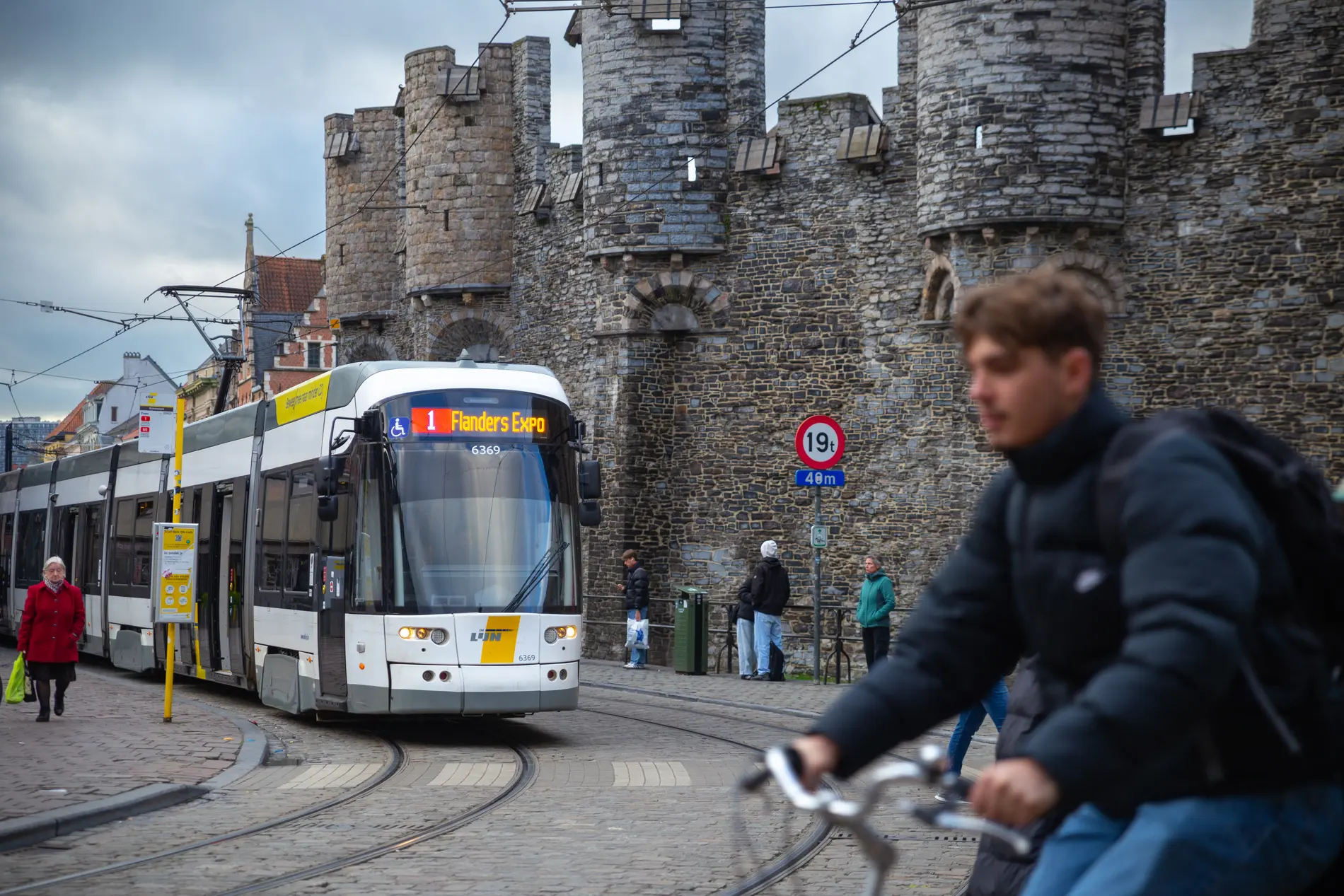 Ein Radfahrer fährt vorbei, dahinter fährt eine Tram. Die Stadt wirkt sehr dunkel.