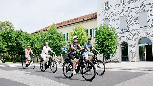 Vier Personen fahren mit elektrischen Fahrrädern in die Arbeit
