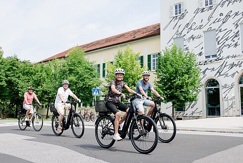 Vier Personen fahren mit elektrischen Fahrrädern in die Arbeit