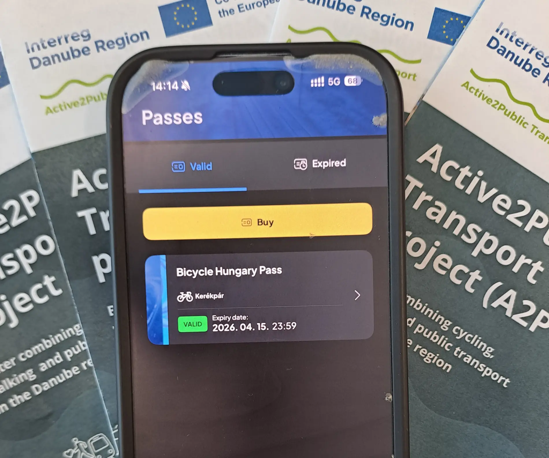 Smartphone showing Bicycle Hungary Pass, A2PT flyers in the background  