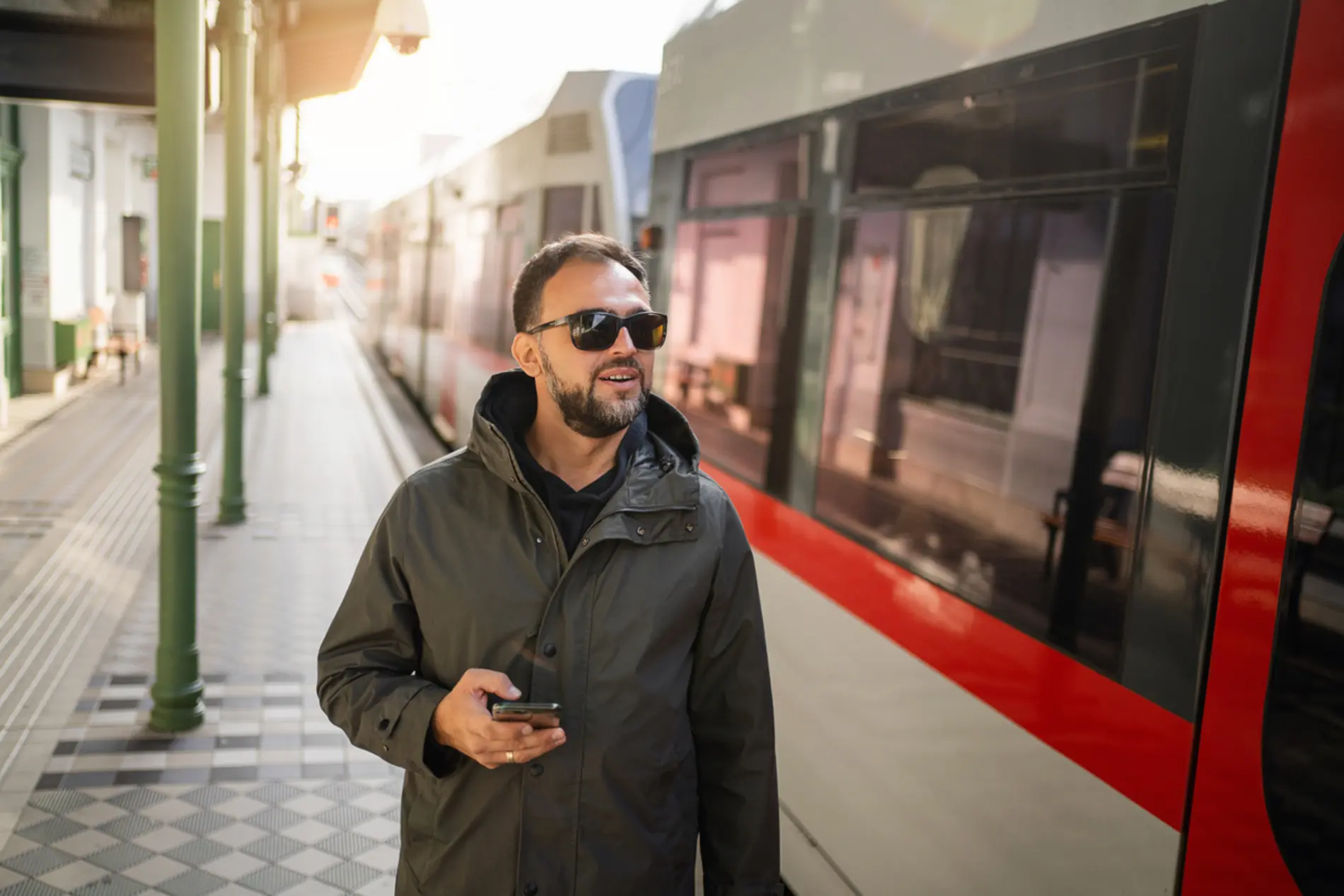 Ein Mann steht mit Handy auf einem Wiener Bahnsteig und wartet auf die U-Bahn