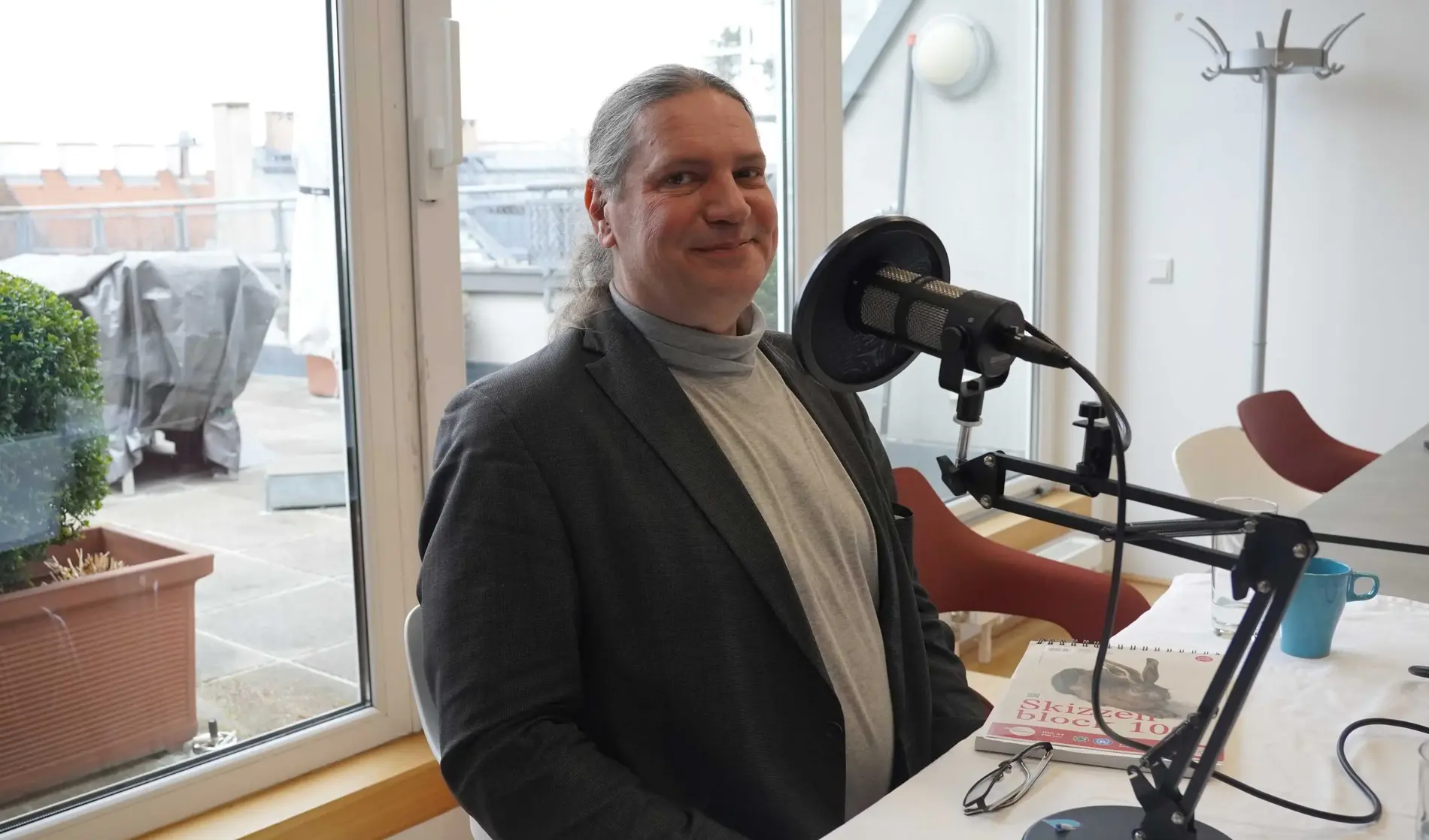 ein Mann vor einem Mikrofon lächelt in die Kamera