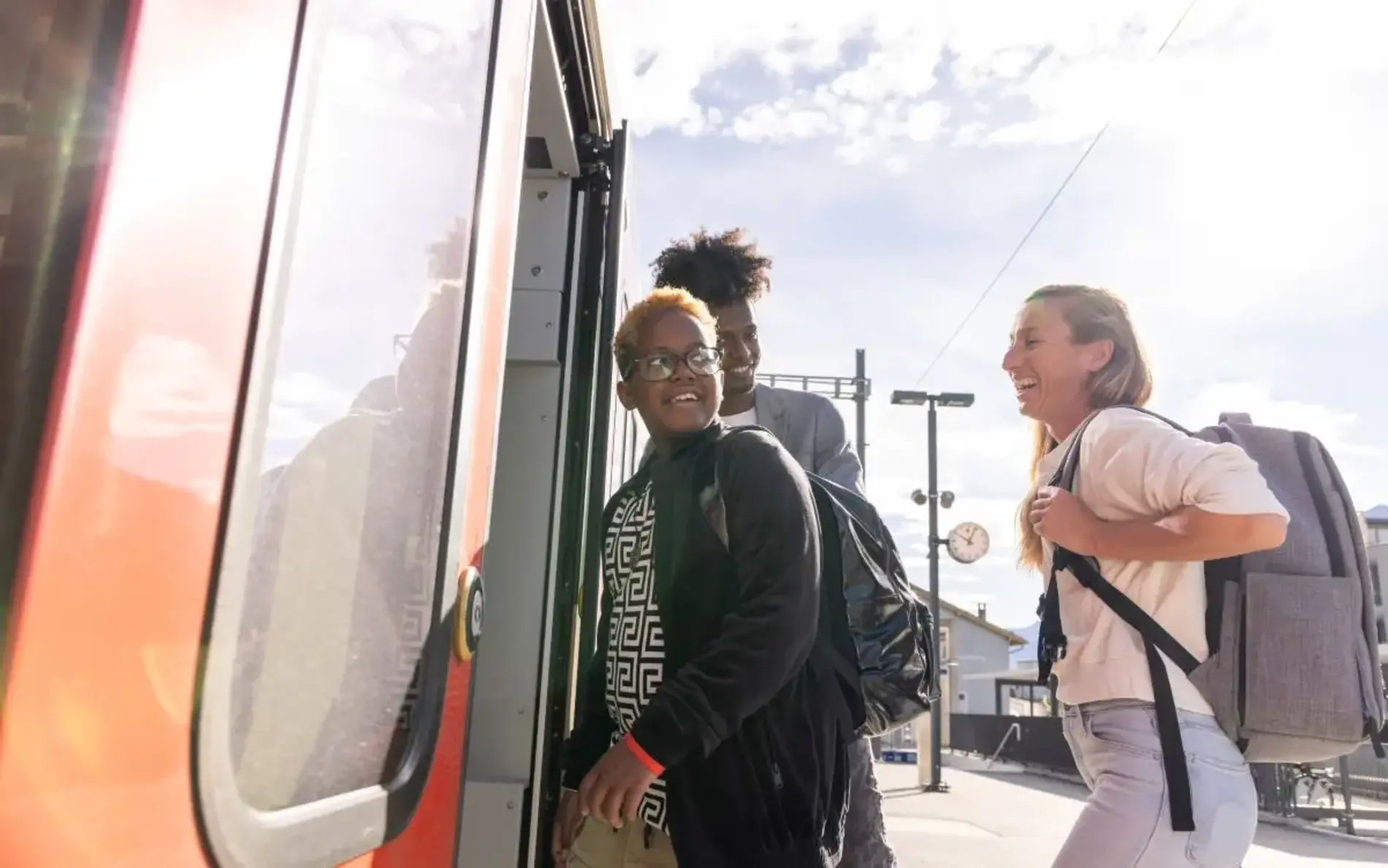 3 Personen steigen in den Zug, eine hat einen Rucksack dabei