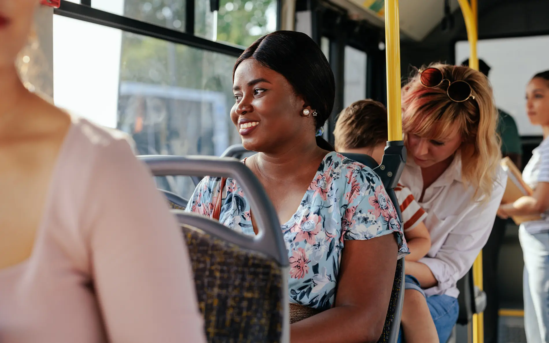 Person sitzt im Bus, schaut aus dem Fenster und lächelt.