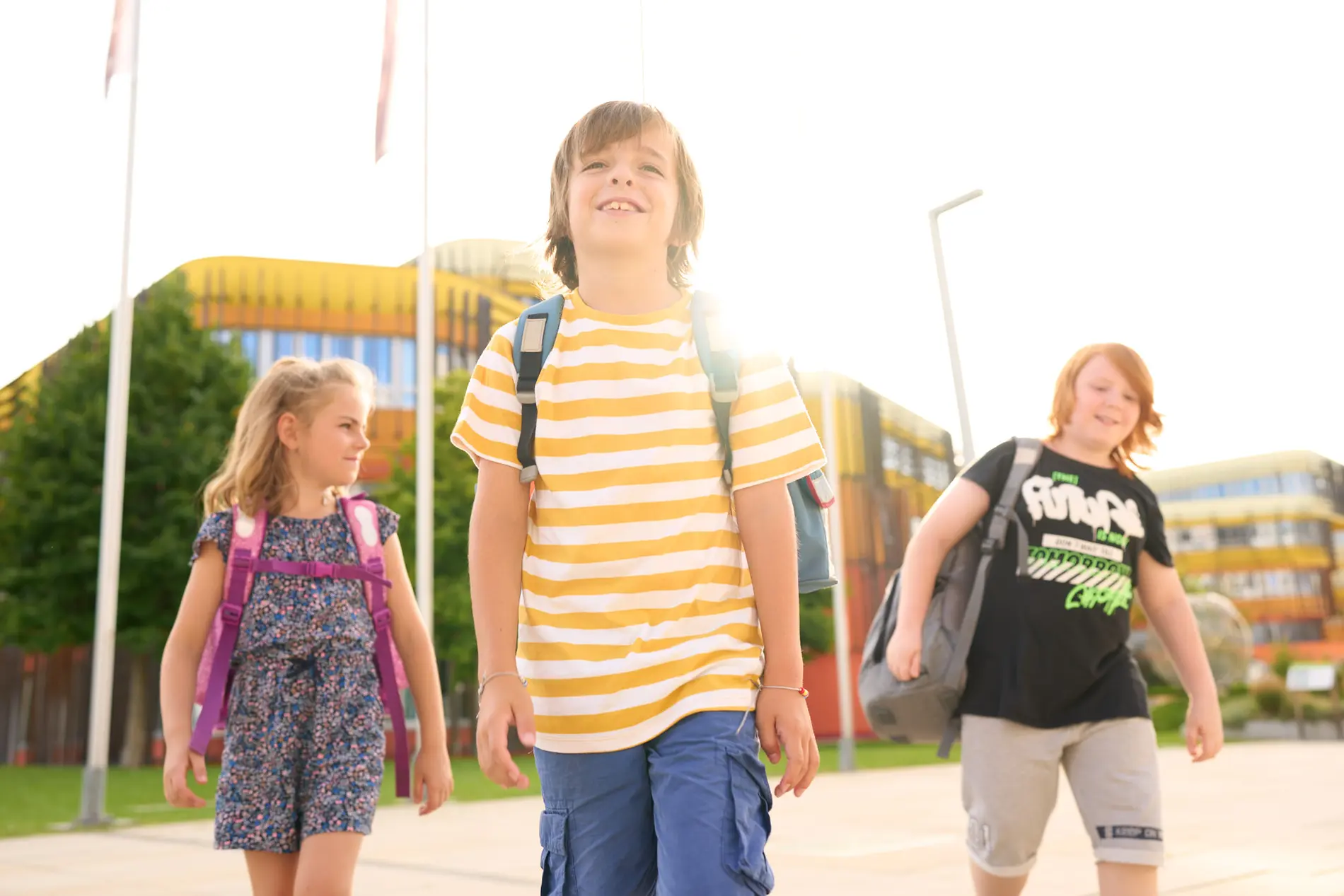 Drei Kinder mit Rucksack am Schulweg