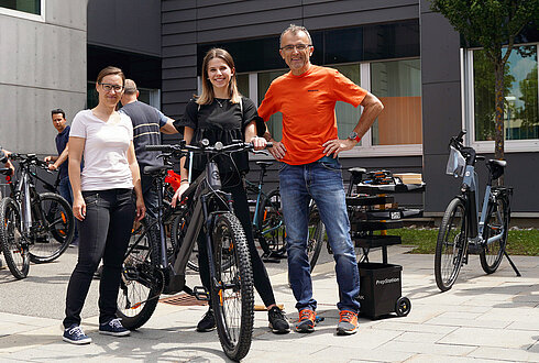 Drei Personen posen mit Rad