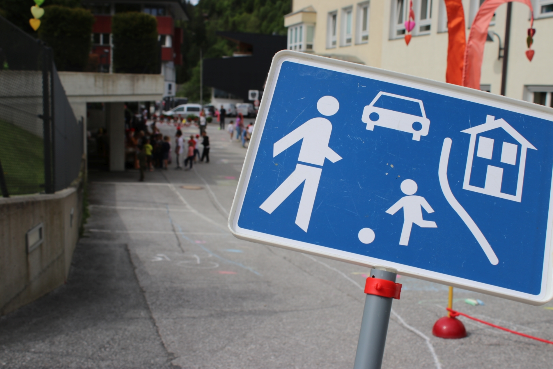 Spielstraße Schild, dahinter ein aufgebauter Parcour auf der Straße