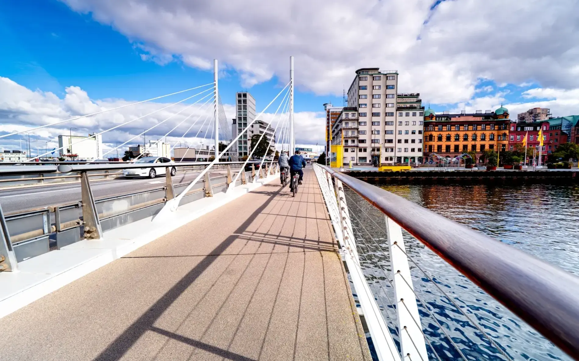 Radbrücke in Malmö über einen dunkelblauen Fluss. 2 Fahrradfahrer auf der Brücke