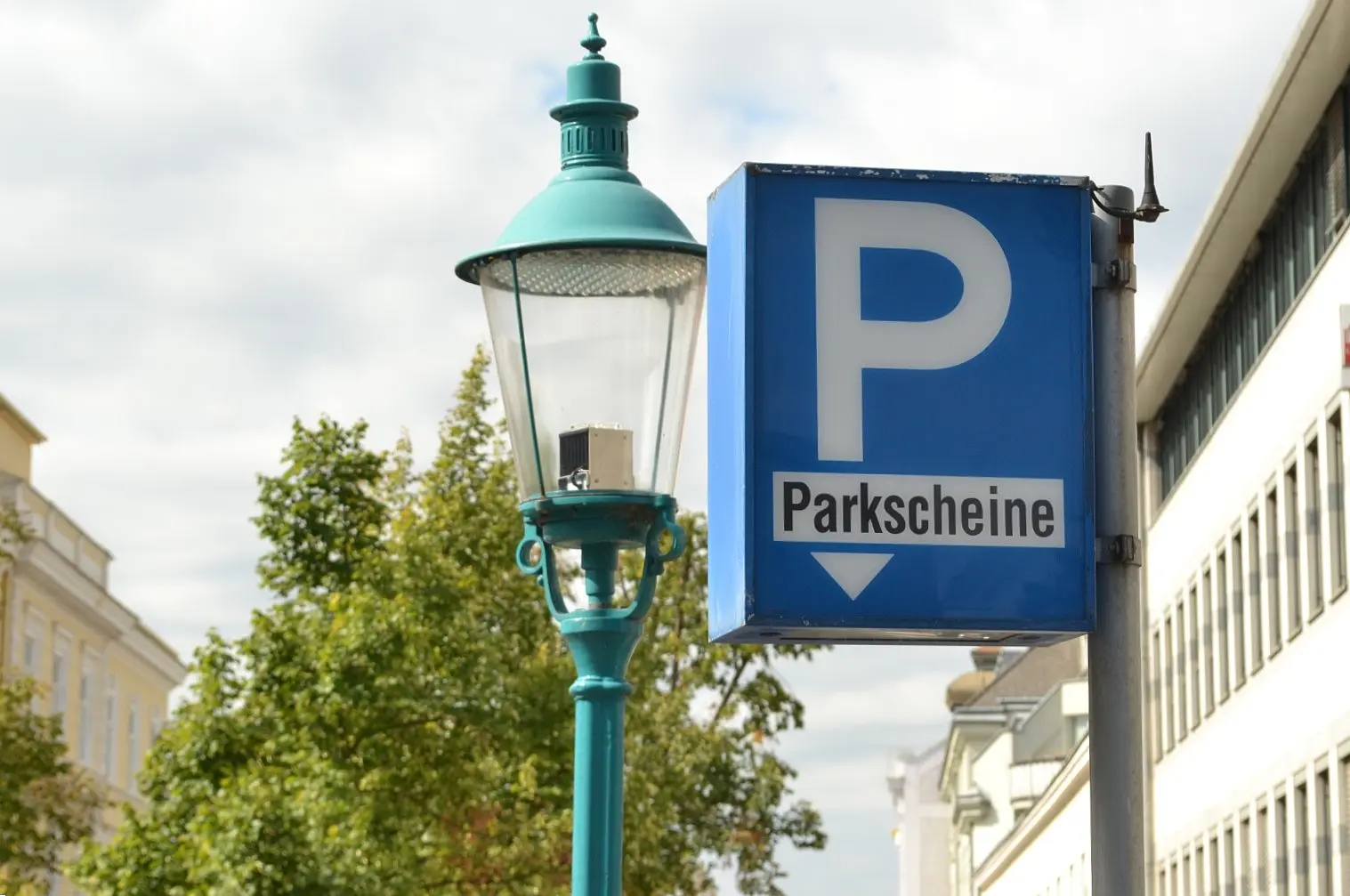 Schild Parkscheine zeigt nach unten, im Hintergrund eine Straßenlaterne