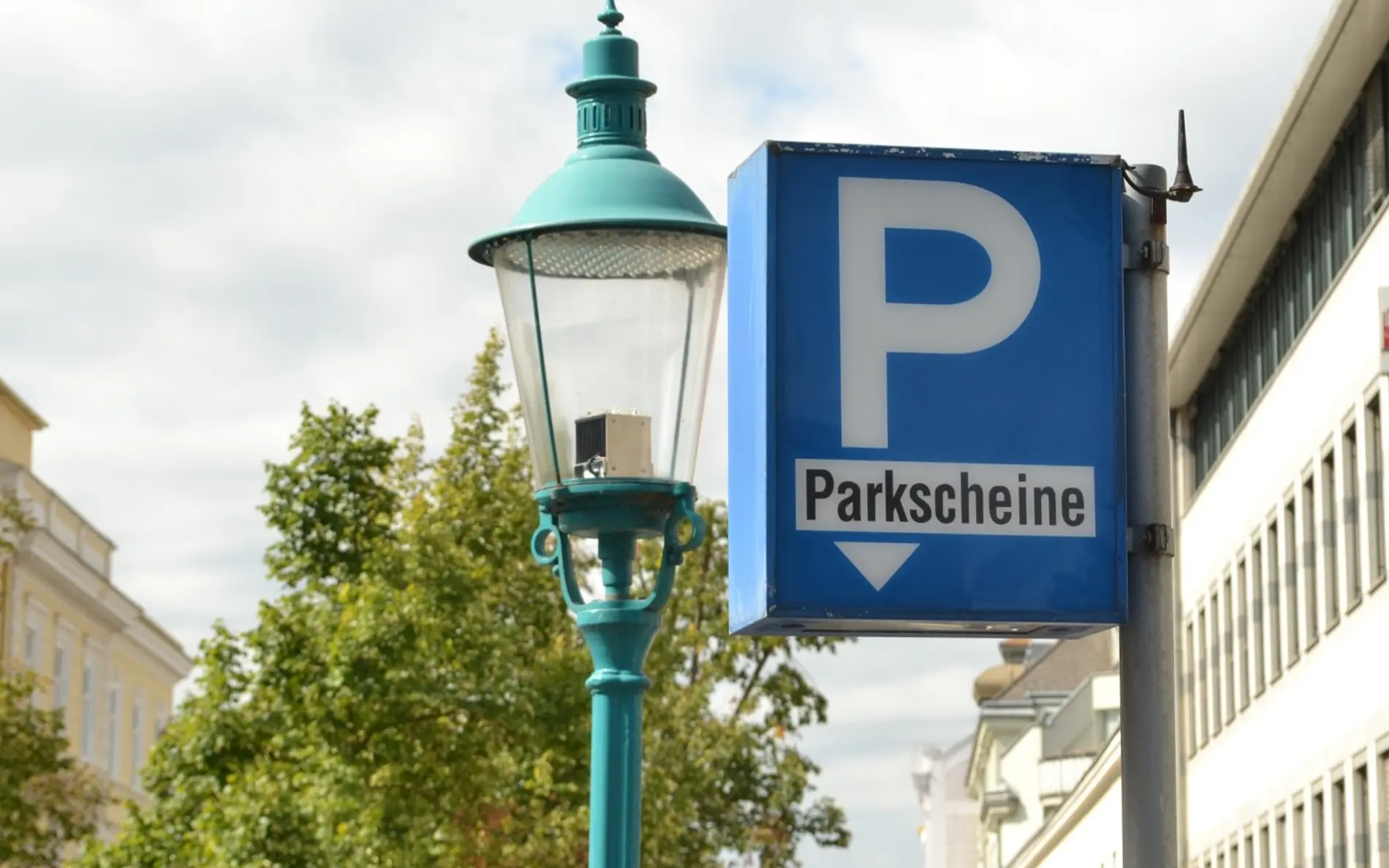 Schild Parkscheine zeigt nach unten, im Hintergrund eine Straßenlaterne