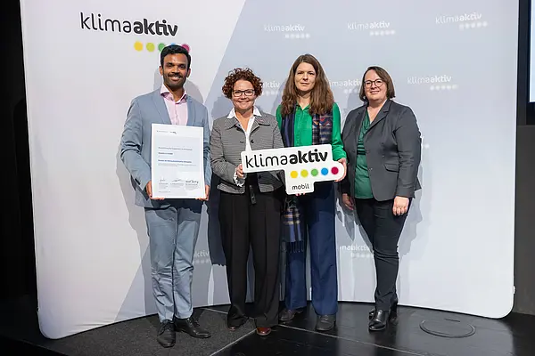 4 Personen mit Urkunde und klimaaktiv Schild schauen in die Kamera
