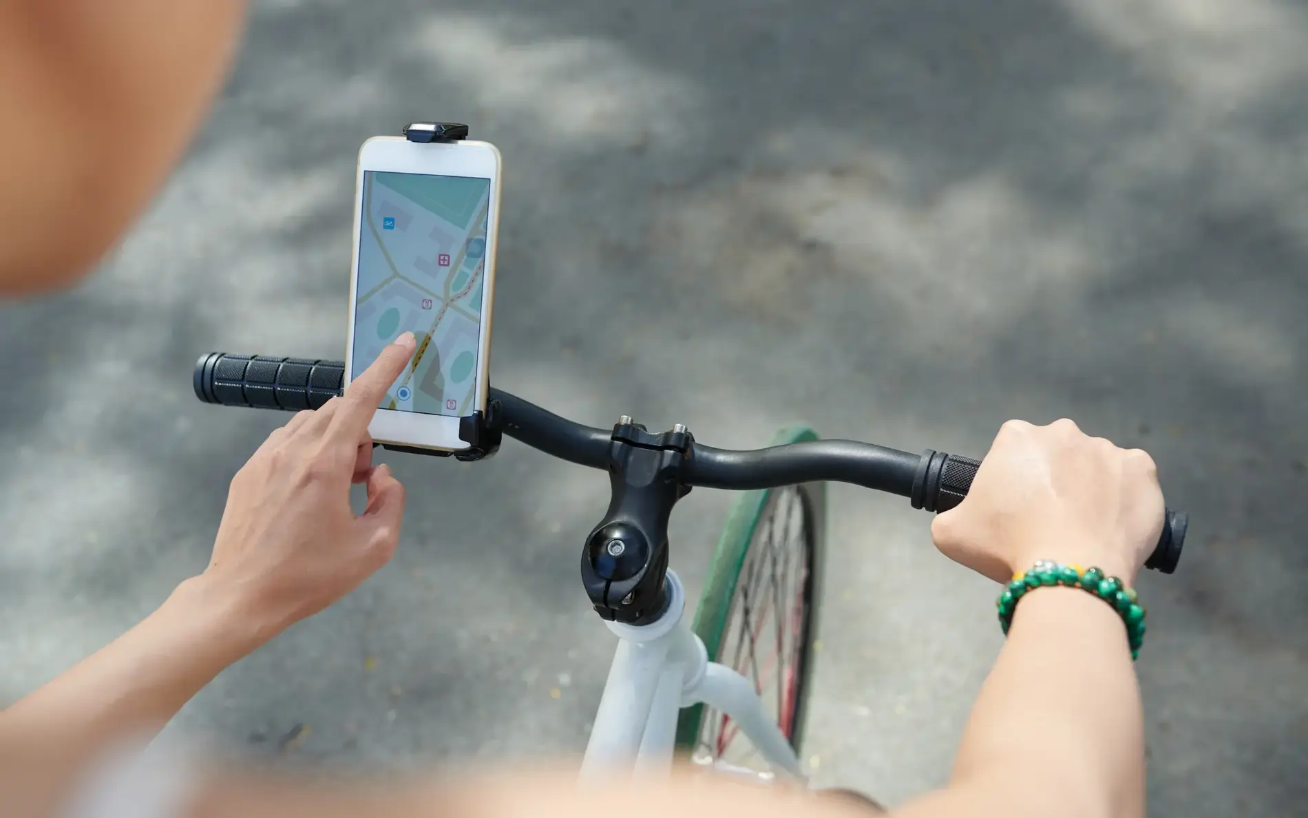 Smartphone am Radlenker befestigt. Ein Finger navigiert und verfolgt den Streckenverlauf.