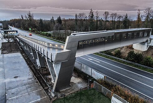 Fuß- und Radbrücke über Straße führt zu einem Gebäude