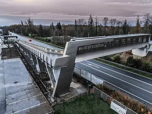 Fuß- und Radbrücke über Straße führt zu einem Gebäude