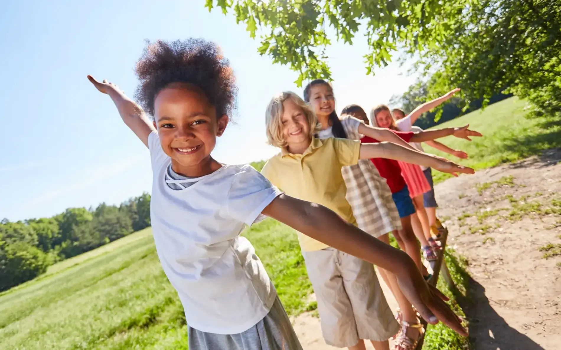 Mehrere Kinder balancieren auf einem Balken im Freien