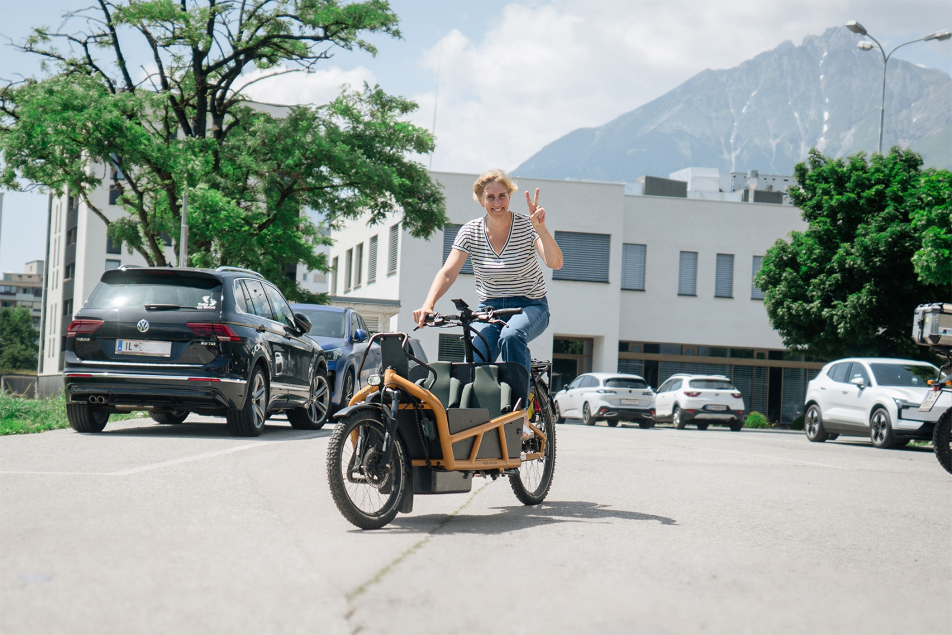 Eine Frau fährt im Sommer auf einem Transportrad über die Straße.