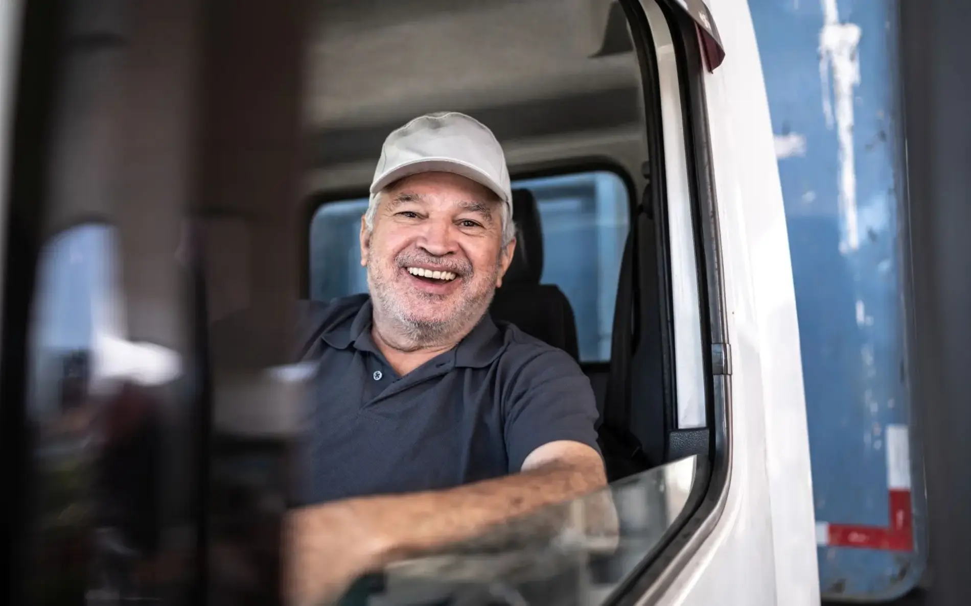 mittelalter Mann mit Schildkappe lächelt aus dem LKW raus