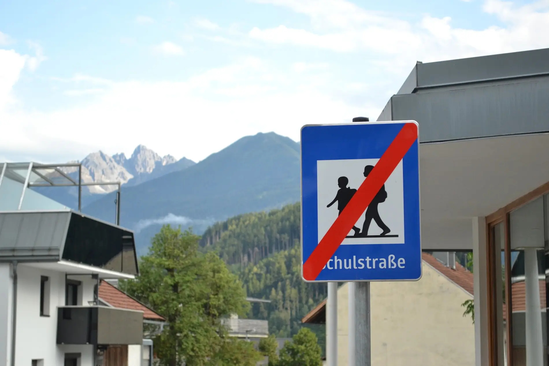 Schild Schulstraße Ende, dahinter Berge und Gebäude