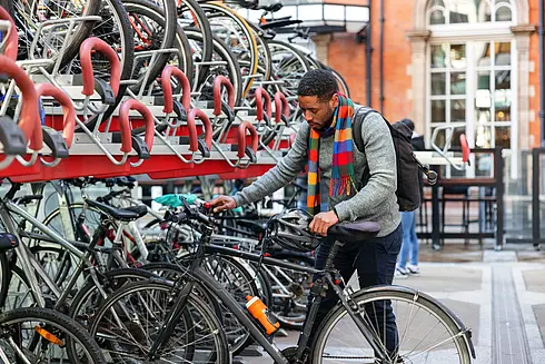 Mann befestigt Fahrrad an einer Doppelstockparker Radabstellanlage