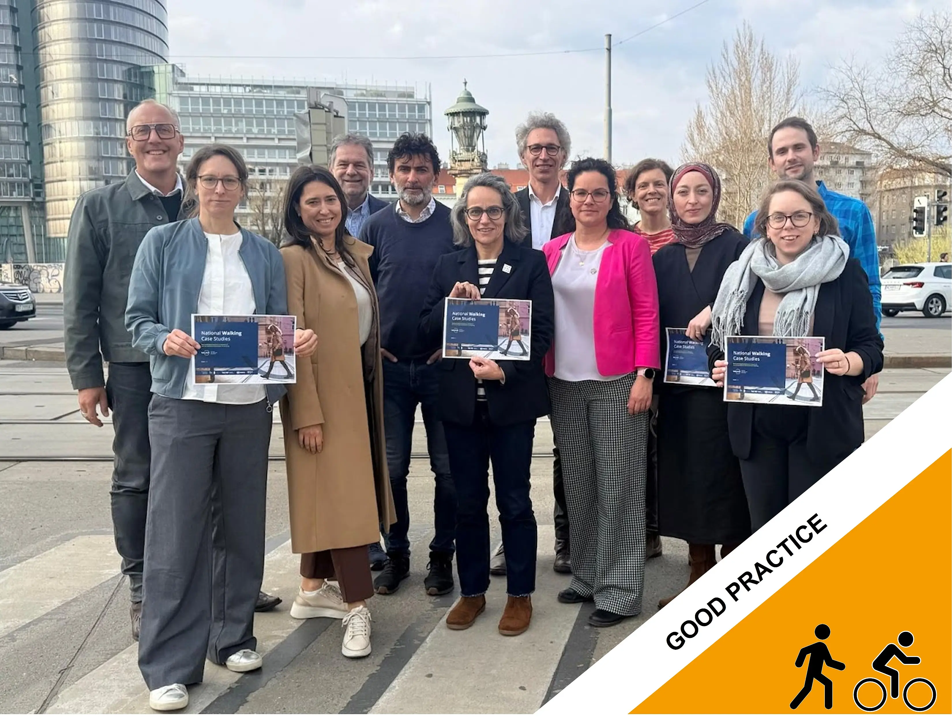 A group of participants at THE PEP project stand outdoors in an urban setting holding project flyers, with modern buildings and a tower visible in the background.